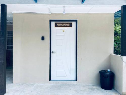 a white door with a sign on it next to a trash can at Inap Desa R'Sawit Pintu B in Sekincan