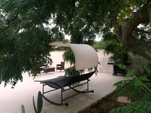 a chair sitting on a patio under a tree at Villetta Le Cesine in Torre Specchia Ruggeri