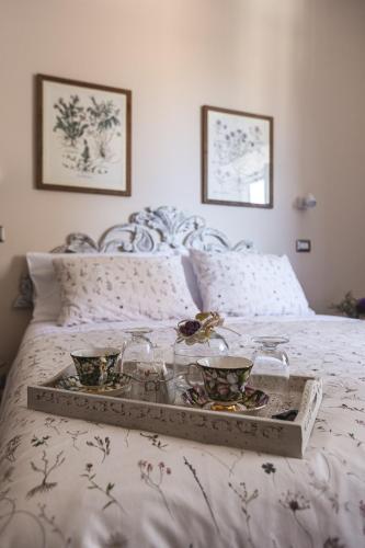 a tray with bowls and glasses on a bed at Residenza D'Epoca Il Grifoncello in Montepulciano