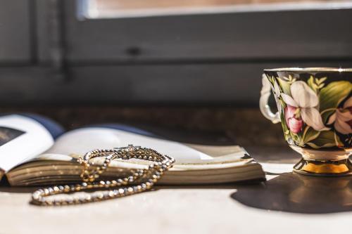 a coffee cup and a book on a table with a necklace at Residenza D'Epoca Il Grifoncello in Montepulciano