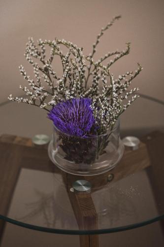 a glass vase with purple flowers on a glass table at Residenza D'Epoca Il Grifoncello in Montepulciano
