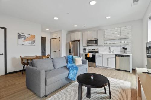 a living room with a gray couch and a kitchen at CozySuites on Mass with garage parking #8 in Indianapolis
