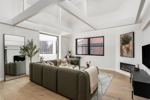 a living room with a couch and a tv at The Henrietta Apartments by Urban Rest in Sydney