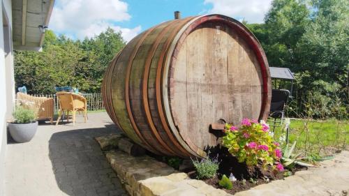 a large wooden barrel in a garden with flowers at Ferienwohnung Hühn in Mülbach
