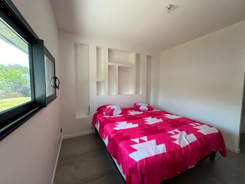 une chambre avec un lit avec une couette rouge et une fenêtre dans l'établissement Maison St Maurice, à Saint-Maurice-lʼExil