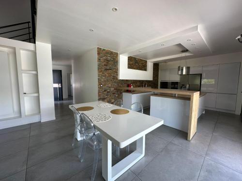 - une cuisine avec une table blanche et des chaises dans l'établissement Maison St Maurice, à Saint-Maurice-lʼExil