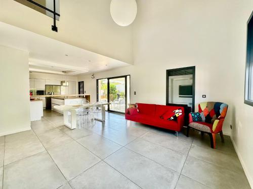 un salon avec un canapé rouge et une cuisine dans l'établissement Maison St Maurice, à Saint-Maurice-lʼExil