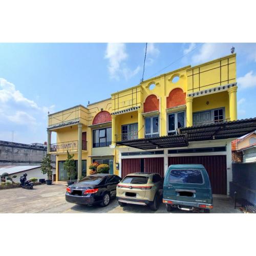 a yellow building with cars parked in a parking lot at RedDoorz Syariah near Universitas Muhammadiyah Bungo in Muarabungo