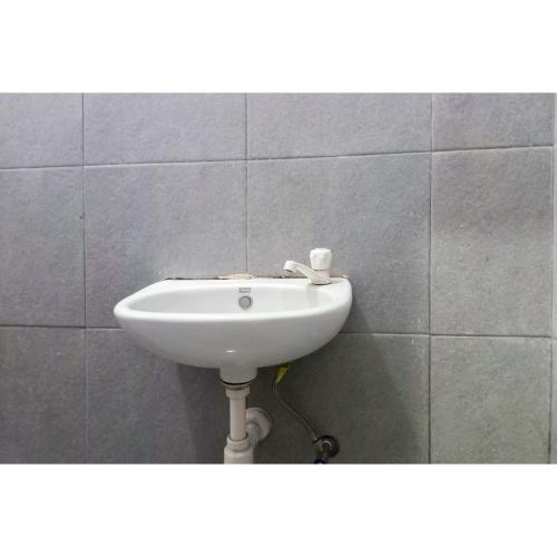 a white sink in a tiled wall at RedDoorz Syariah near Universitas Muhammadiyah Bungo in Muarabungo