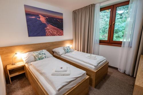 a hotel room with two beds and a window at Hotel Jasná in Demanovska Dolina