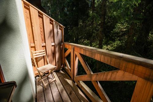 a wooden porch with a chair sitting on it at Hotel Jasná in Demanovska Dolina