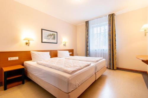 a bedroom with a large white bed with a window at Strandnahe Wohnung im Dünenpark Haus 31 in Binz