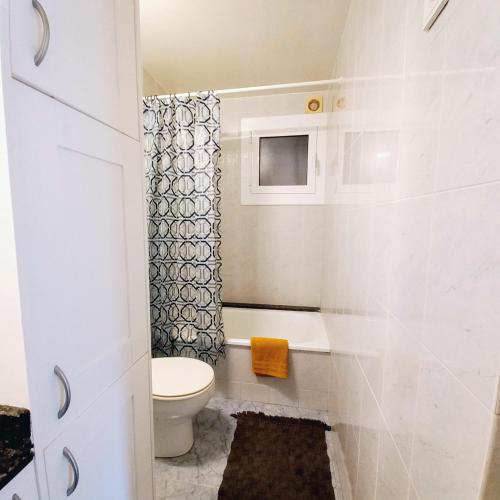 a white bathroom with a toilet and a shower at Apartament Sant Feliu de Guixols in Sant Feliu de Guixols