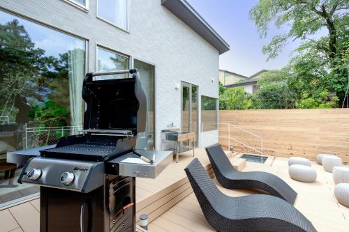 a patio with a grill and two chairs on a deck at Smart Villa Hakone Gora - Smart Villa 箱根強羅 in Hakone