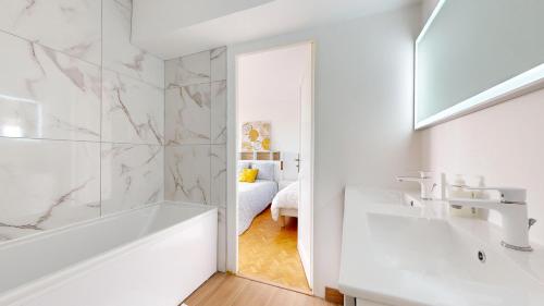 une salle de bain blanche avec une baignoire et un lavabo dans l'établissement Les terrasses de Saint Georges 100m clim Parking, à Toulouse