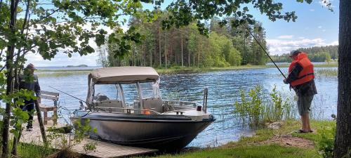 a man standing on a dock with a boat on the water at Pikkumirri, pikkumökki in Joensuu