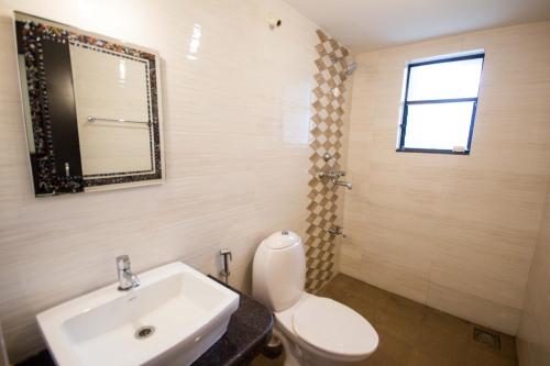 a bathroom with a sink and a toilet and a mirror at 2BHK -Balcony & Pool View -Monarch Palms, Cadolim in Candolim