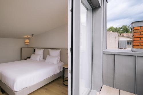 a bedroom with a bed and a window at Hôtel Majestic in Bordeaux