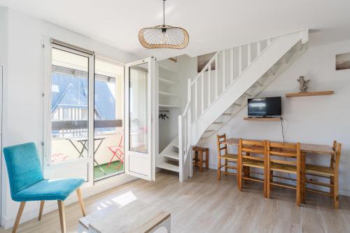 un salon avec une table et des chaises et un escalier dans l'établissement Duplex du bord de mer - Appt à 50m de la plage, à Villers-sur-Mer