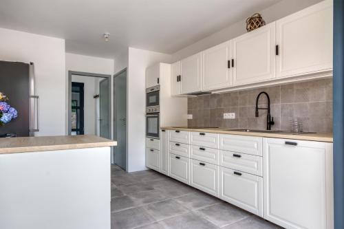 a kitchen with white cabinets and a sink at Le Logis de la Pierre Bleue - Maison avec piscine in Férel
