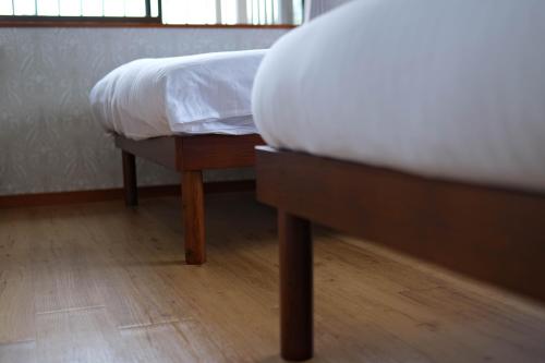 a bedroom with a bed with white sheets and wooden floors at HOEI villas Fujisan全景 富士山 河口湖中心区 in Fujikawaguchiko