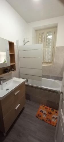 une salle de bain avec une baignoire, un lavabo et un miroir dans l'établissement Gite Lamalpapoche, à Quézac