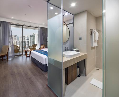 a bathroom with a bed and a sink and a mirror at Gonsala Hotel Nha Trang in Nha Trang