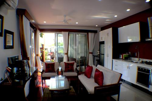 a living room with white furniture and red pillows at Kia Orana Villas and Spa in Rarotonga