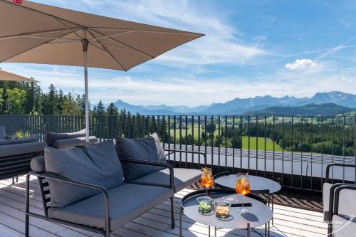 a patio with a couch and an umbrella at PANORAMA Allgäu Spa Resort in Seeg