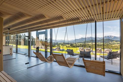 a room with chairs and a balcony with mountains at PANORAMA Allgäu Spa Resort in Seeg