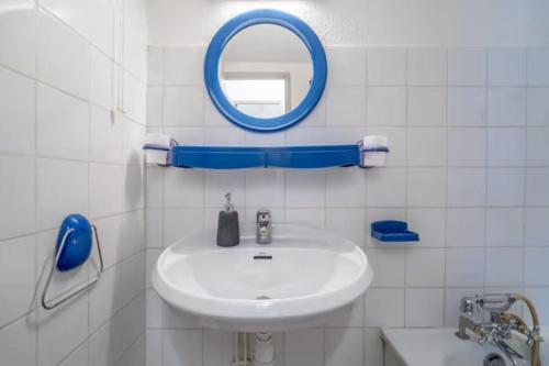 une salle de bain blanche avec un lavabo et un miroir dans l'établissement Le Cap 27 vue sur mer, terrasse, au Cap d'Agde