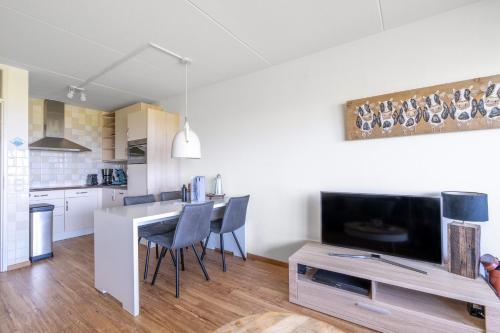 a kitchen and living room with a table and a tv at Appartementencomplex Juliana 102 in De Koog