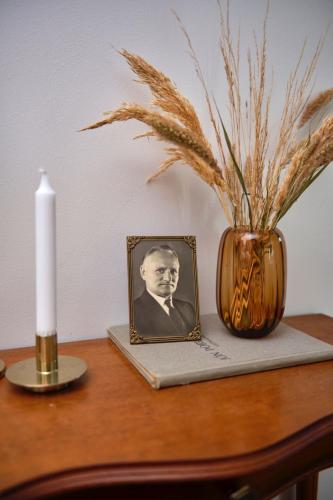 a candle and a vase on a table with a picture at Kidafell Farmhouse in Mosfellsbær