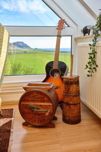 a guitar and a drum sitting next to a window at Kidafell Farmhouse in Mosfellsbær