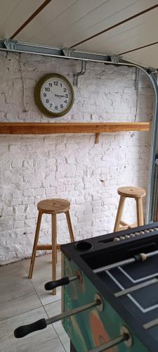 a clock on a wall next to two stools at Les roses d'Olga in Aubechies