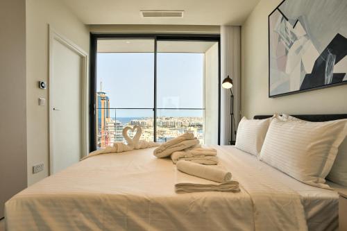 a bedroom with a large bed with towels on it at Luxury Apartment with Panoramic Sea views in Mercury Towers in St. Julianʼs