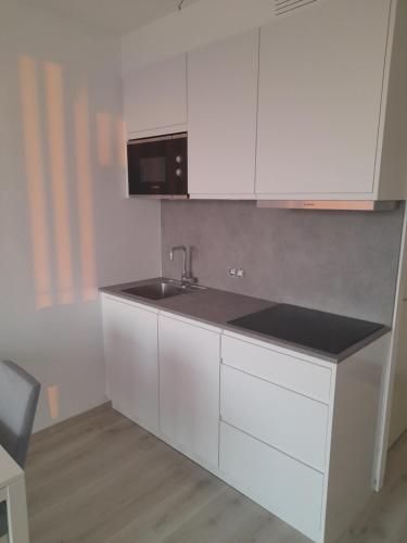 een witte keuken met een spoelbak en een magnetron bij Studio Seasant in Nieuwpoort