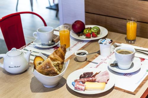 a table topped with plates of food and cups of coffee at Brit Hotel Toulouse Colomiers – L’Esplanade in Colomiers