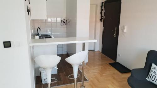 a kitchen with two white stools and a counter at Apartman Savic 1 in Bijeljina