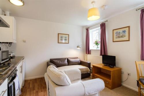 a living room with a couch and a tv at Westminster College Cottages, Cambridge in Cambridge
