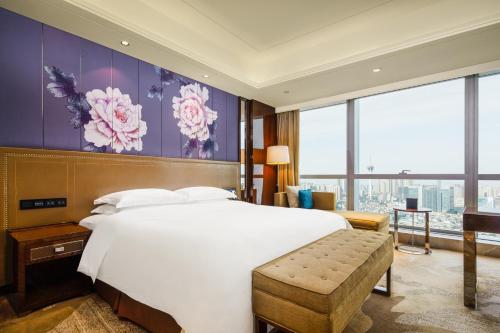 a bedroom with a large white bed and large windows at Minyoun Chengdu Dongda Hotel in Chengdu