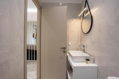a white bathroom with a sink and a mirror at Ourania Apartment 2 in Pentati