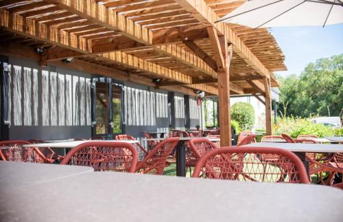 a table with red chairs and umbrellas at a restaurant at Hotel du Parc Euromédecine by AKENA in Montpellier