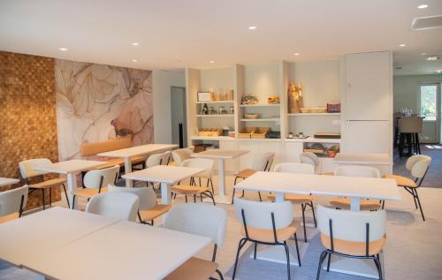 a restaurant with tables and chairs and a counter at Hotel du Parc Euromédecine by AKENA in Montpellier