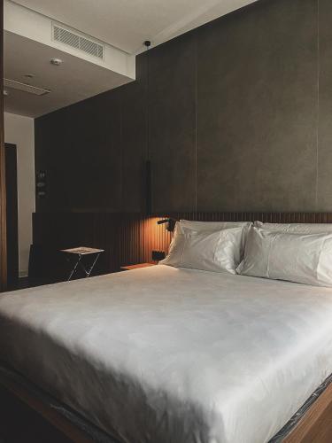 a bedroom with a large white bed with a black wall at J Maluni City Hotel in Rome