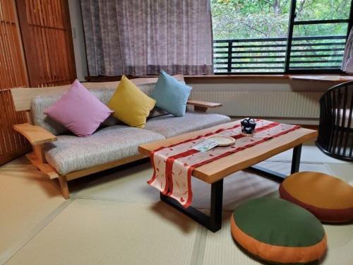 a living room with a couch and a coffee table at 蔵王温泉 岩清水料理の宿 季の里 in Zao Onsen