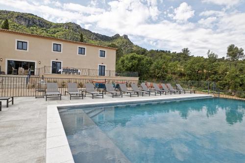 une piscine avec des chaises longues et un bâtiment dans l'établissement Un joli hameau au coeur du vignoble de l'Escarelle et de la Provence Verte, à La Celle