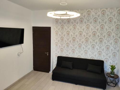 a living room with a black couch and a television at 12 senses faliraki sea view in Faliraki