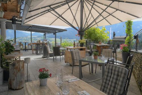a patio with tables and chairs and an umbrella at Hotel und Alpen Apartments mit Sauna - Bürglhöh in Bischofshofen