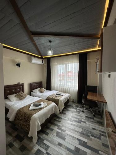 a hotel room with two beds and a desk at Bayrak Suit Home Trabzon in Pelitli